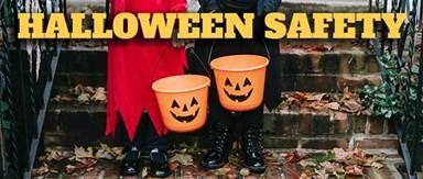 Halloween Safety with two people wearing costumes and holding buckets